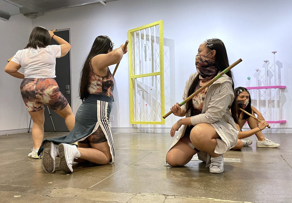 A group of women posed on the floor of an art gallery carrying Filipino Martial Art, Kali sticks