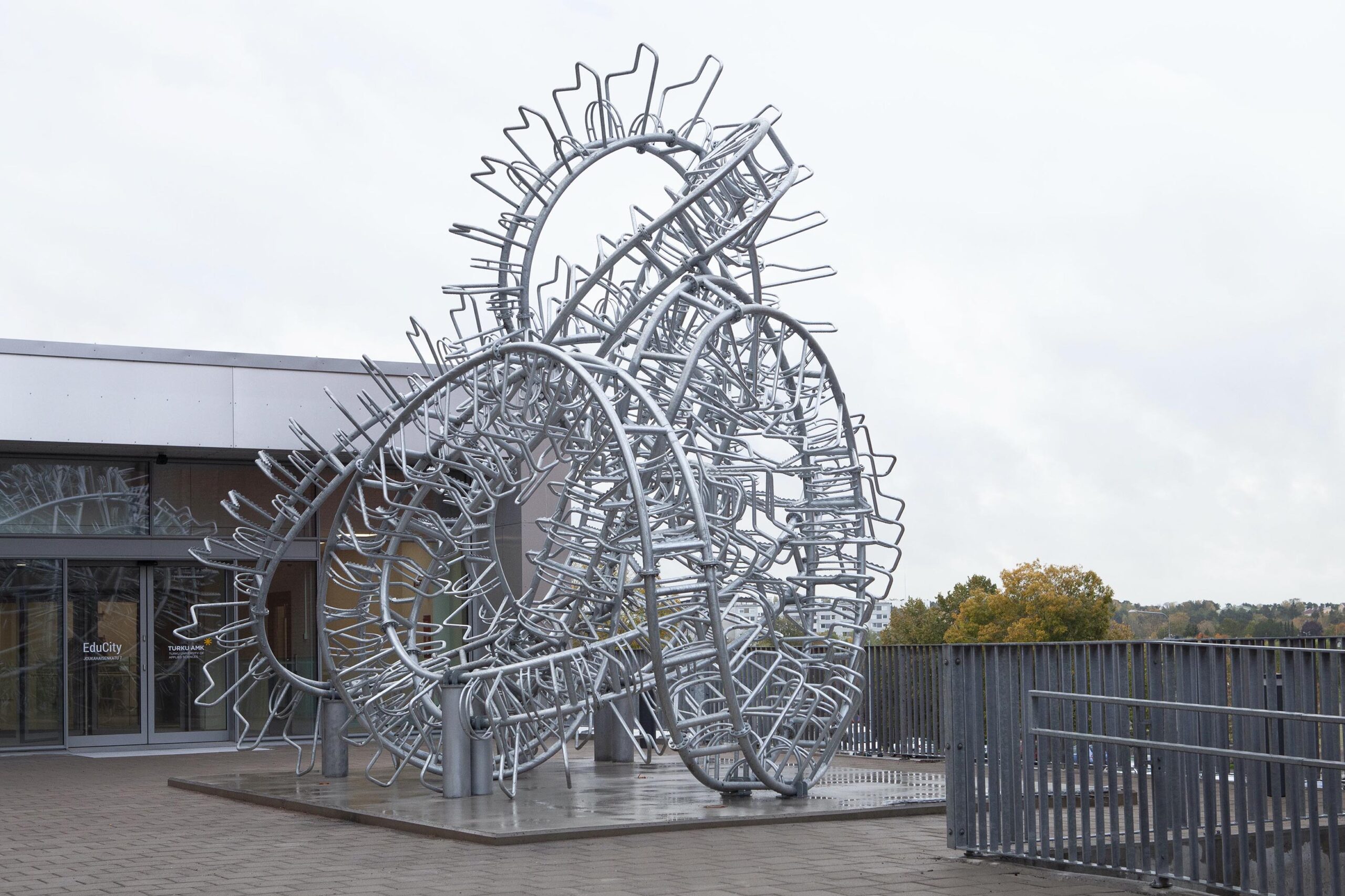 The sculpture consists of 80 metres long bicycle rack bent in meandering forms. The concept of meander pointing humorously to a classic ornament motifs, along with modern concept of meandering in a city, reflecting its surroundings as a central traffic point in the City of Turku where the sculpture is installed.