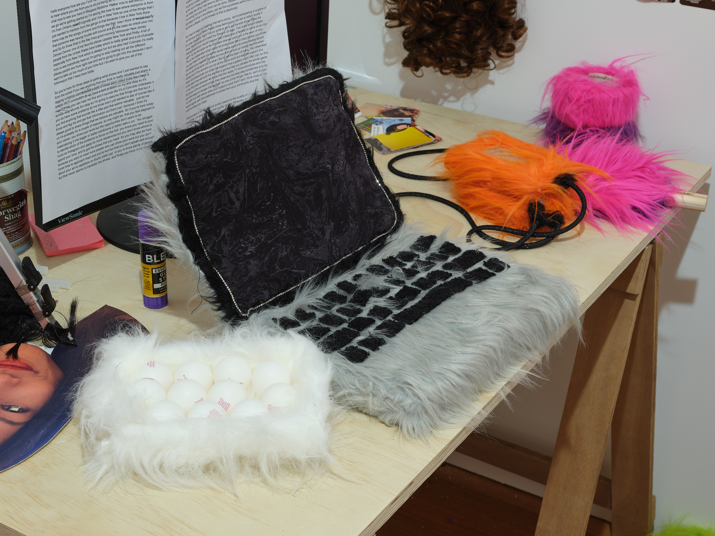 A messy desk with a laptop, hard drives, and duct tape made of faux fur