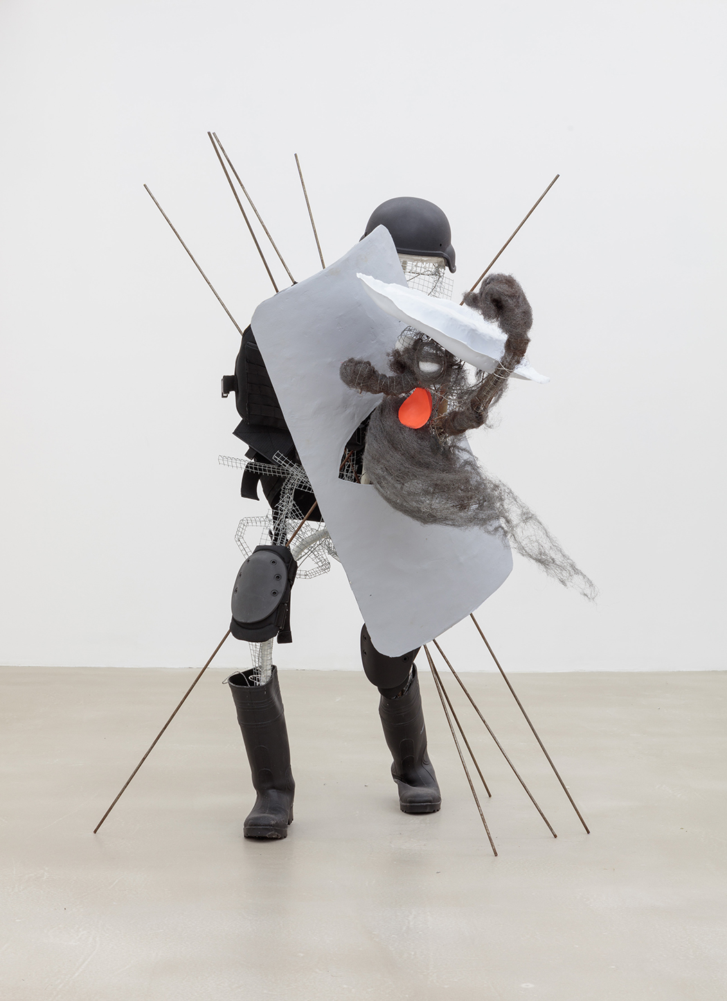 A sculpture using real riot gear and a steel wool figure that does not anatomically align with the riot gear.