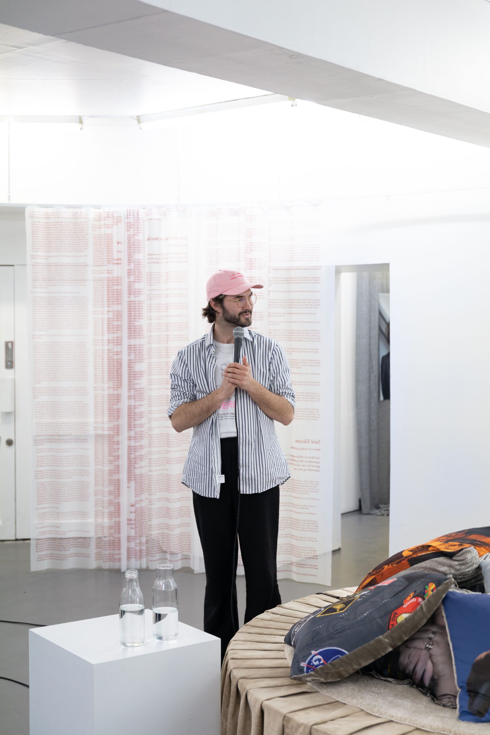 Man standing in a room with a pink cap, blue shirt and black pants