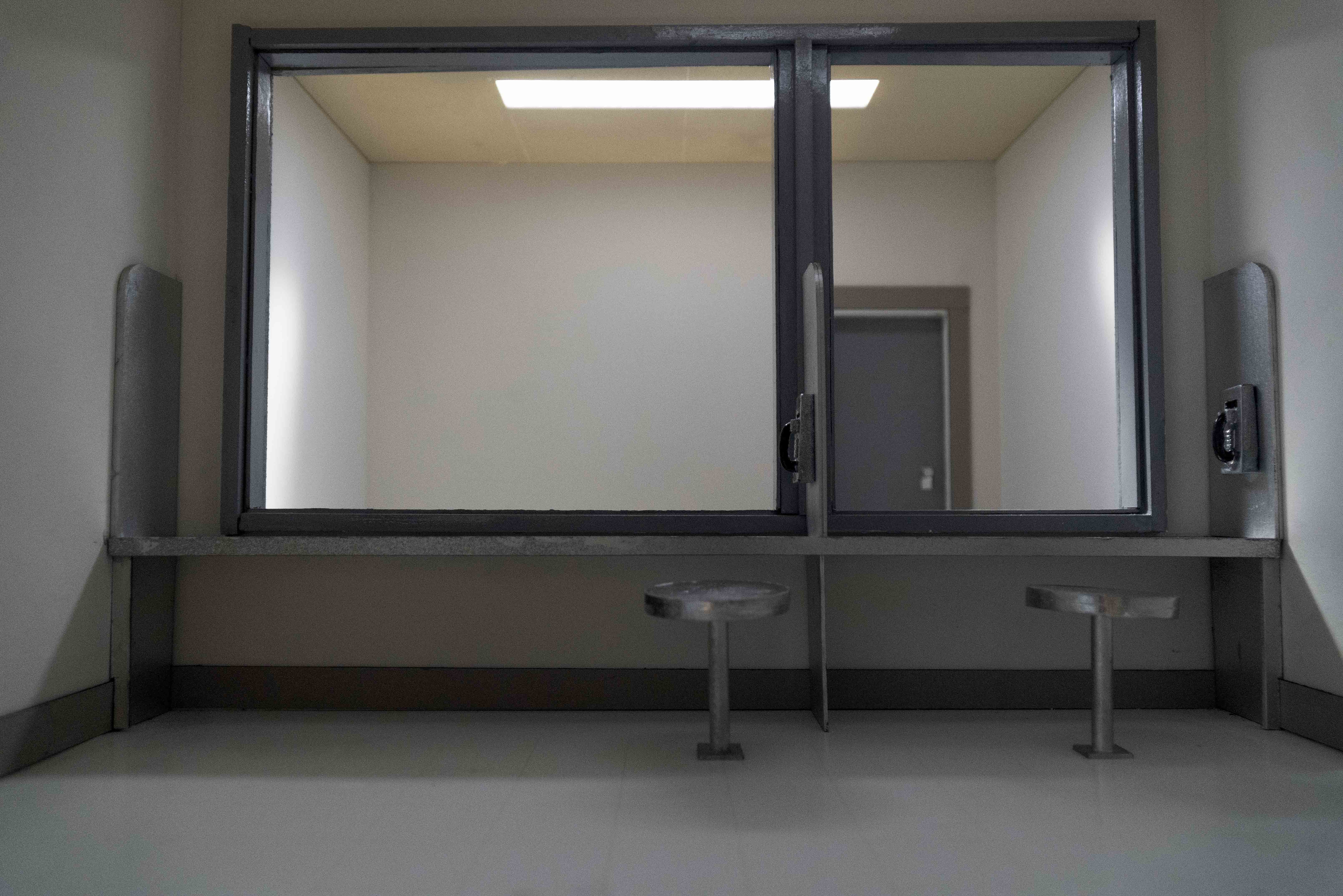 A still of a video that shows a visitation room that appears to be within a prison or other carceral space. The no-contact visitation room is a model reconstruction of the Laval Immigration Detention Centre in Laval Quebec.