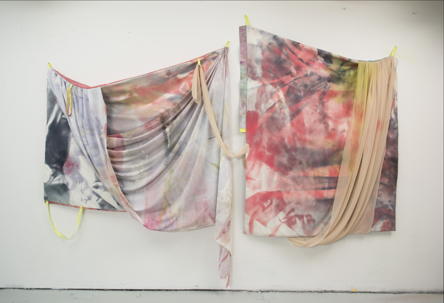 Two panels of fabric connected by sheer draped fabric. Left panel is predominantly grey and white with some pink. Right panel is more pink and peach with some yellow.