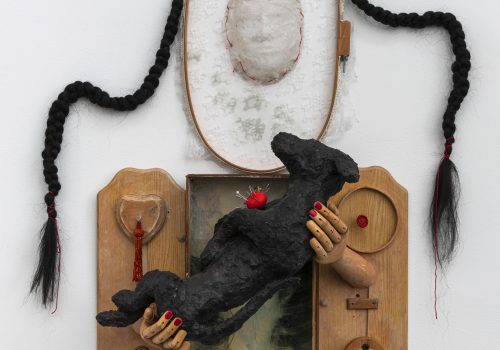 A found object sculpture of a woman holding a black dog.