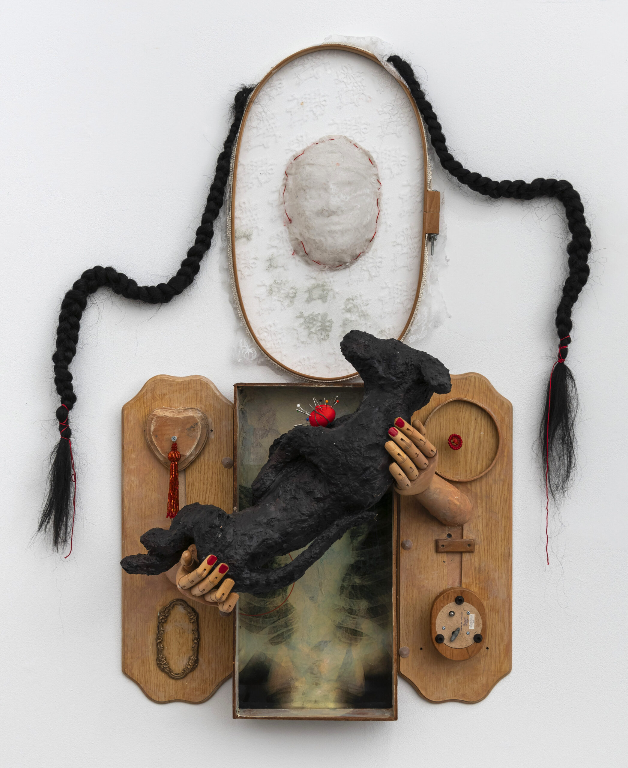 A found object sculpture of a woman holding a black dog.