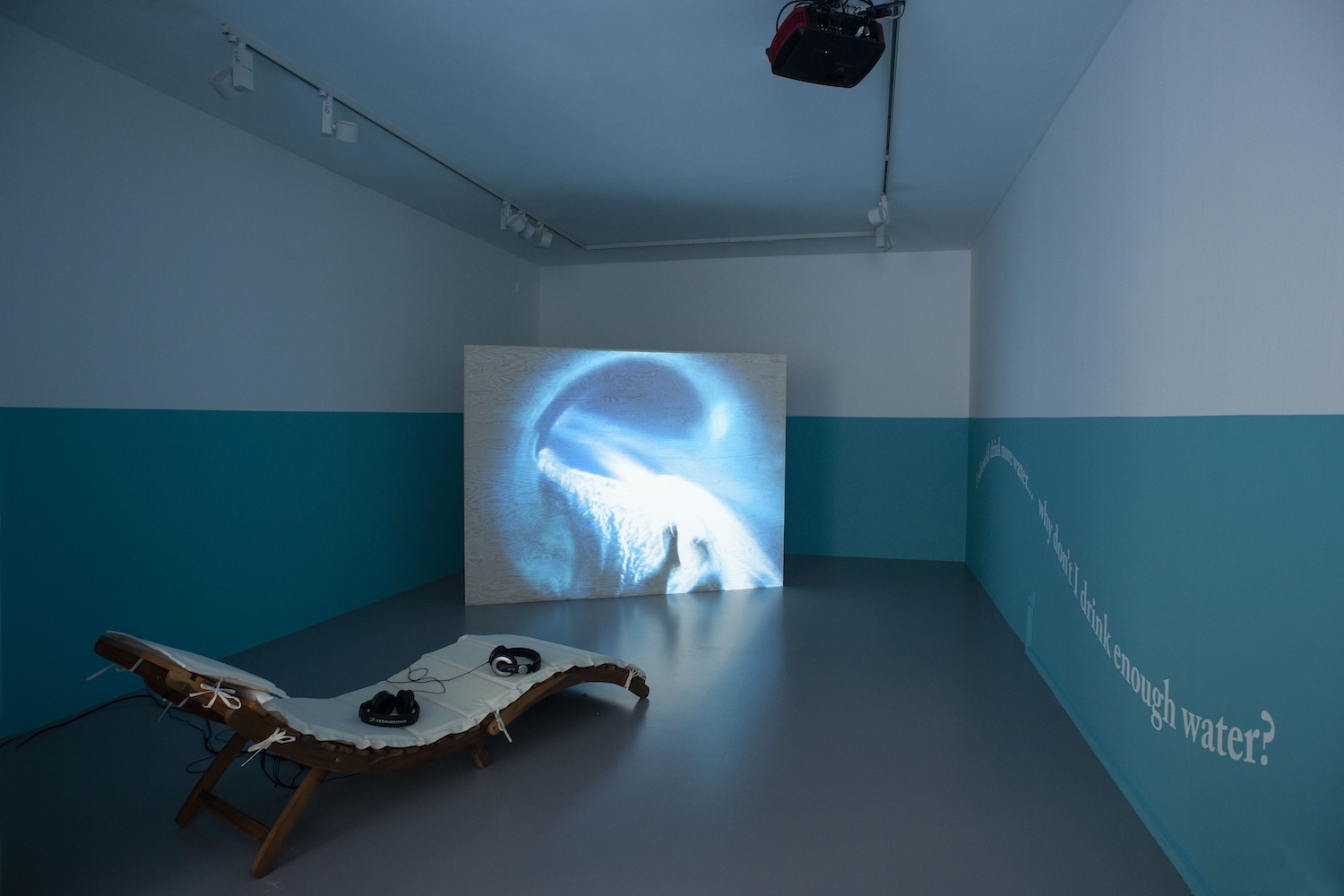 video, vinyl, pine wood, paint, custom sun lounger. Curated by Tania Nasielski.