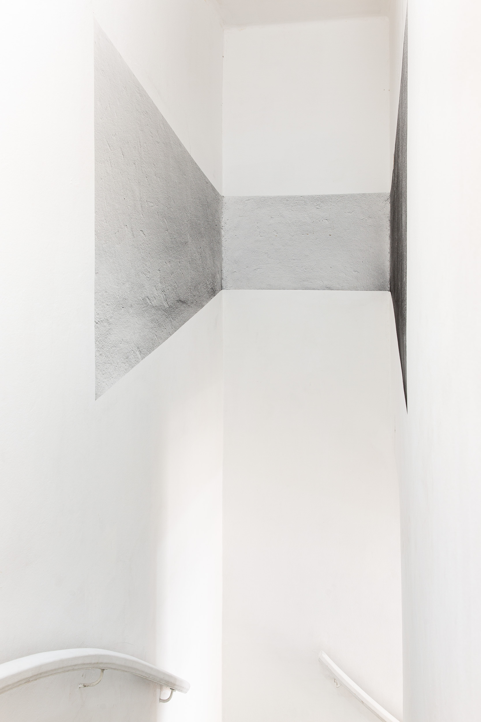A site-specific work where the artist uses charcoal dust to create a drawing inspired by architectural elements of the exhibition space—in this case, an upper staircase corridor. The process begins by marking a perimeter on the wall based on historical perspective references. Charcoal dust is then blown onto the surface without fixative, forming a landscape that evokes the typical dirt of polluted cities.