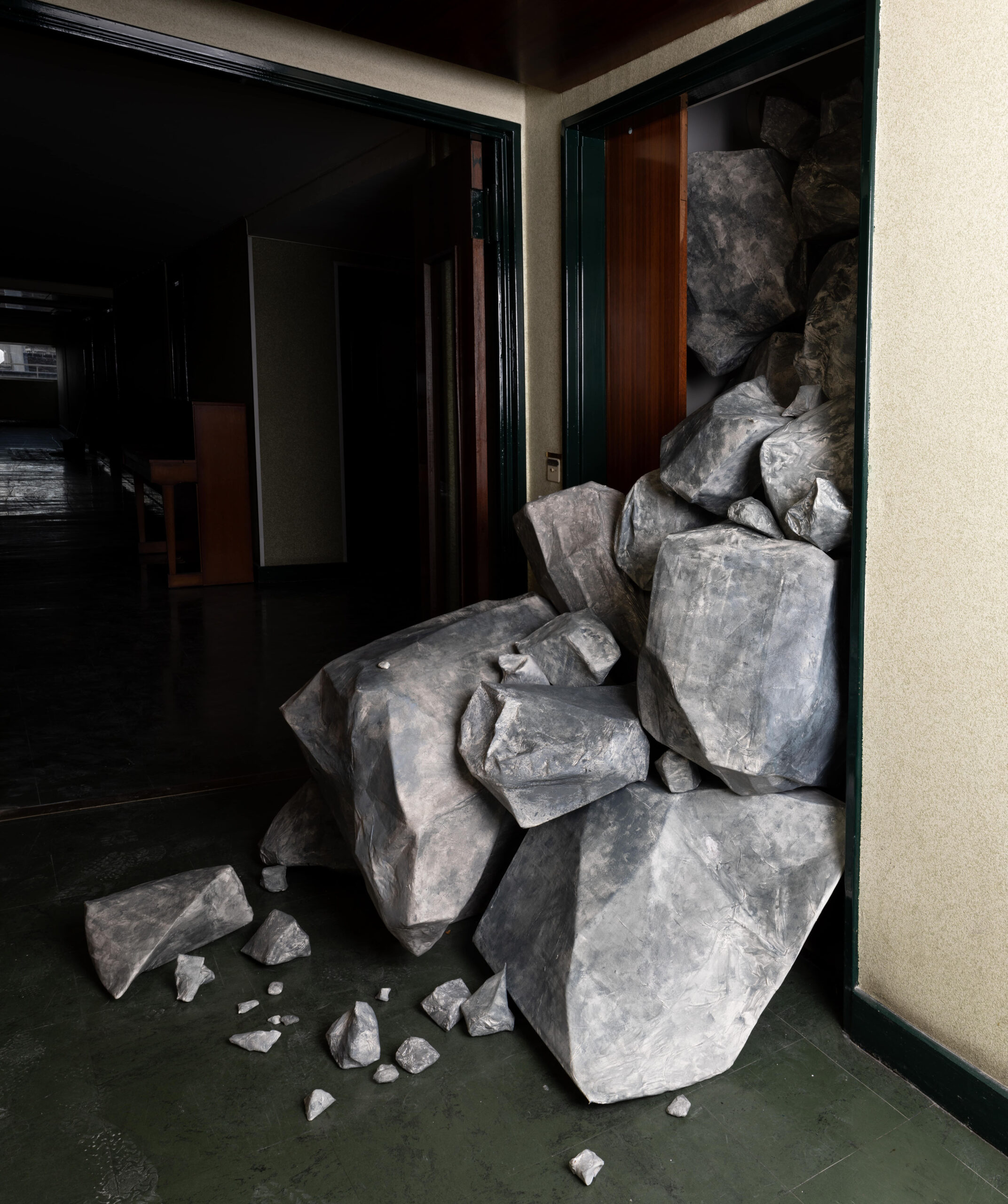 cardboard, paper towels and wall paint - The Wild, Rebounding is an installation that was created for the open studio event at the Cité Internationale des Arts, where the artist was in residence for a few months in 2025. The work - an avalanche of stones or the ruins of buildings that emerge from inside her studio - was exhibited during the period when her studio was supposed to be open to visitors.